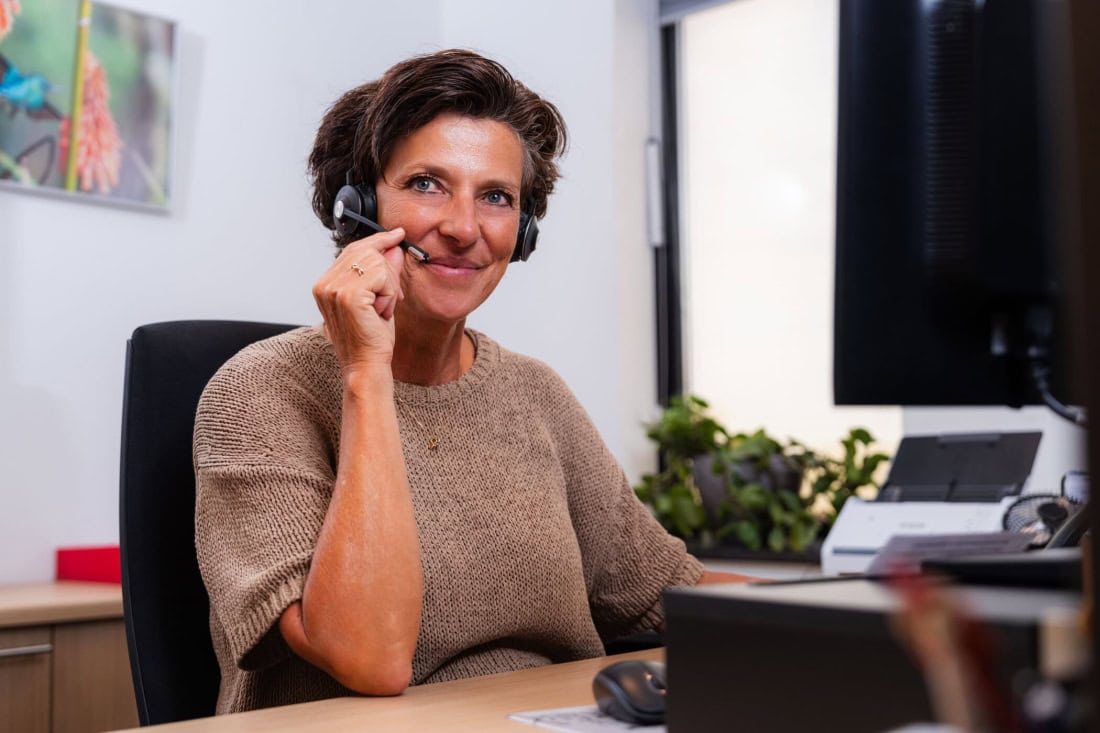 Care worker with headset helps with GP and GP clinic queries.