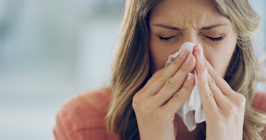 Shot of an attractive young woman feeling ill and blowing her nose with a tissue at home